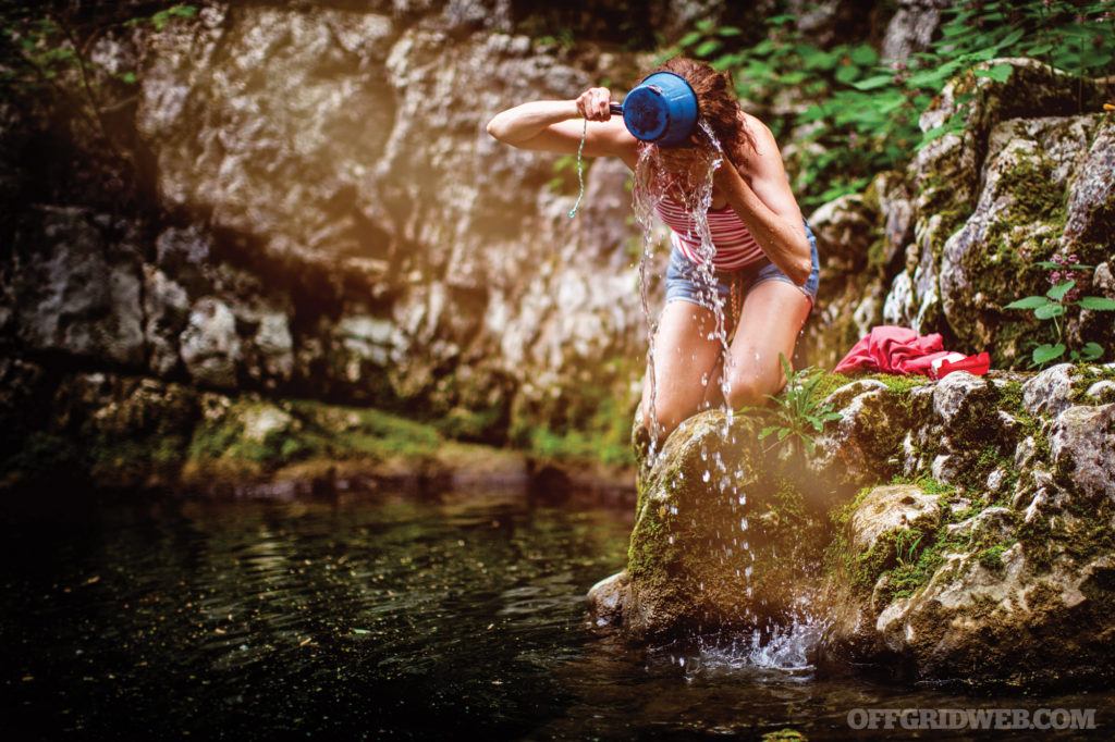 Photo of an adult woman washing her hair in a river.
