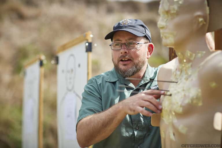 Photo of John Hearne discussing the results on a ballistics dummy at a firing range.
