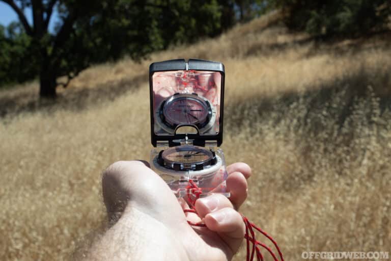 Photo of a hand holding a compass shooting an azimuth.