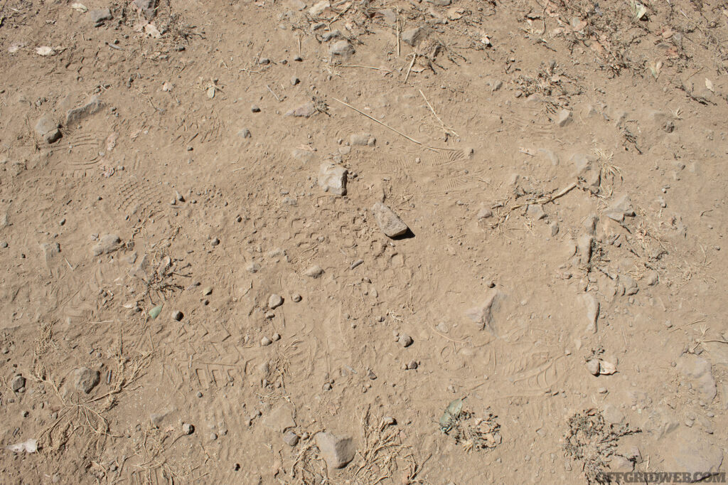 Photo of a mix of foot prints left behind in the dust by numerous people with different types of shoes.