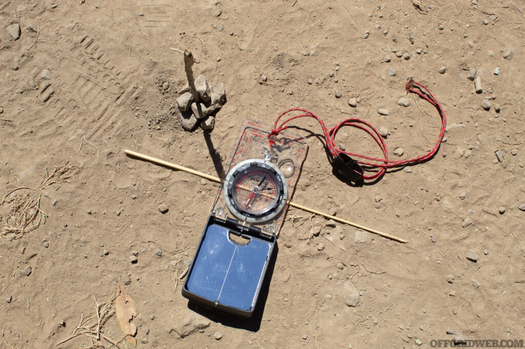 Photo of the east-west line marked with an improvised sundial. A compass is being used to prove the accuracy of this method.