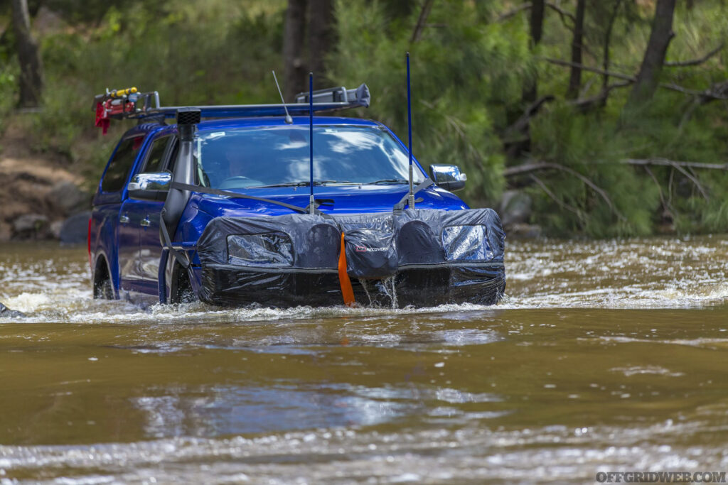 Photo of a customized overlanding SUV driving through a water crossing.