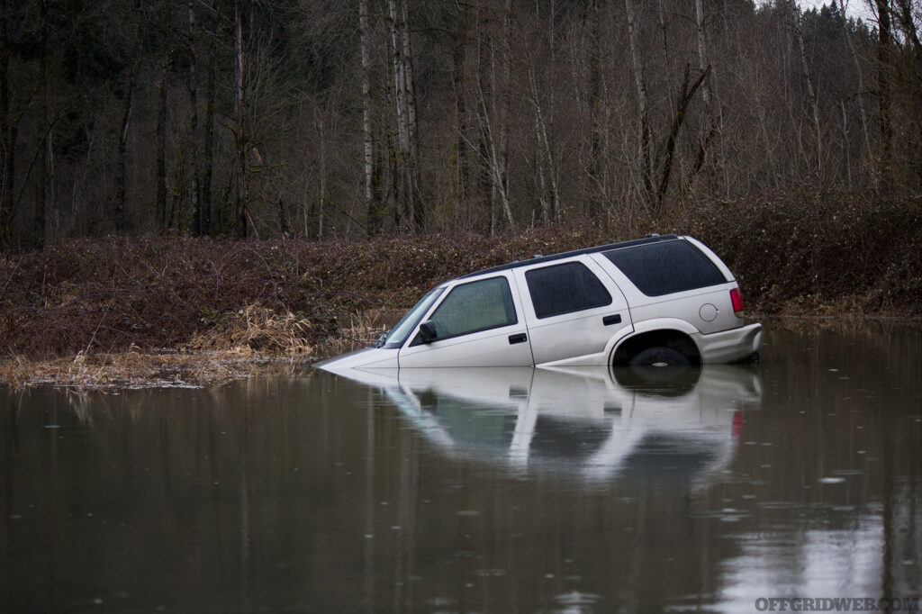 Photo of a flooded SUV with the front end sunk into the water.