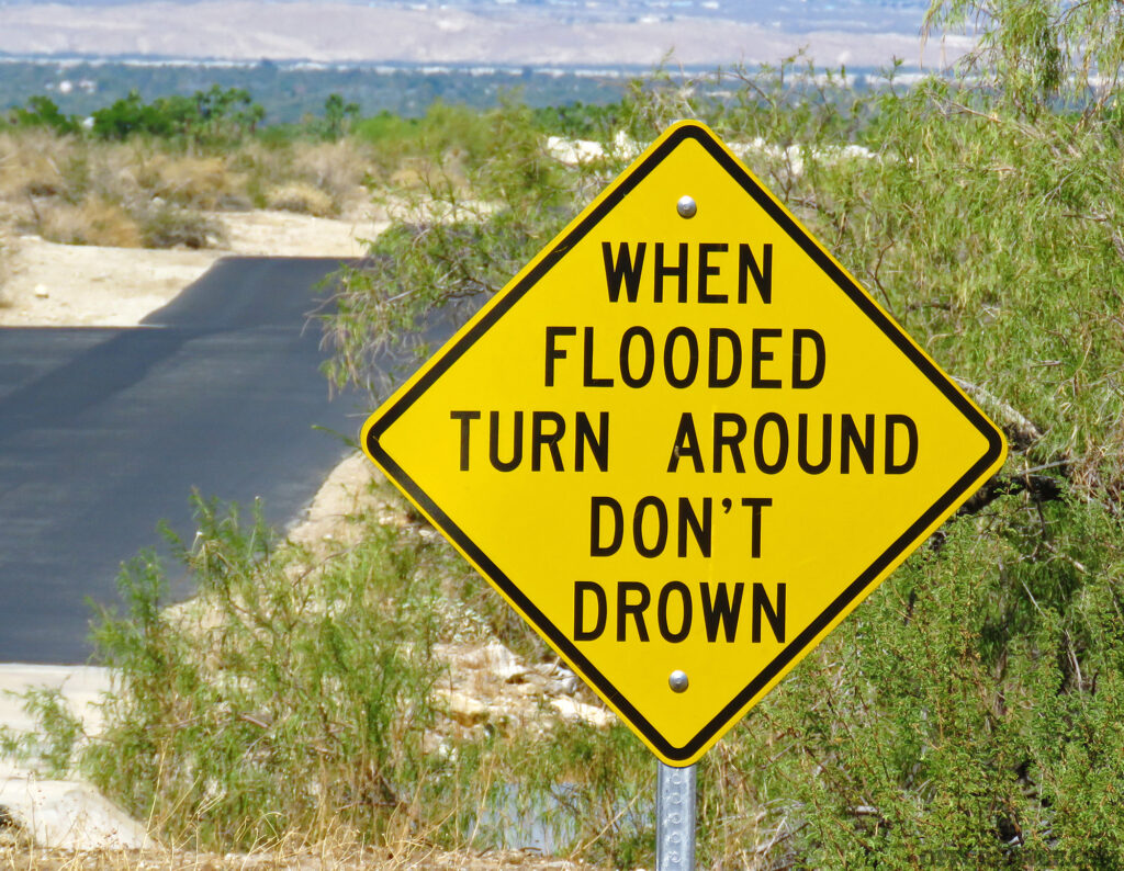 Photo of a flash flood warning sign. telling travelers to turn around when the road is flooded.