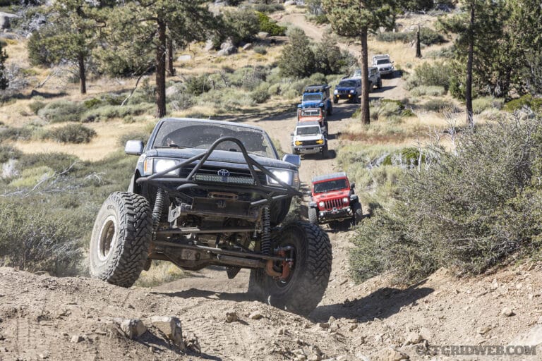 A convoy of overlanding vehicles navigating rocky terrain.