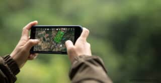 Photo of an adult holding a cell phone sideways to look at a navigation app.