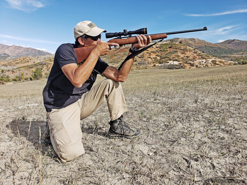 Photo of a man aiming with a firearm from the kneeling position.