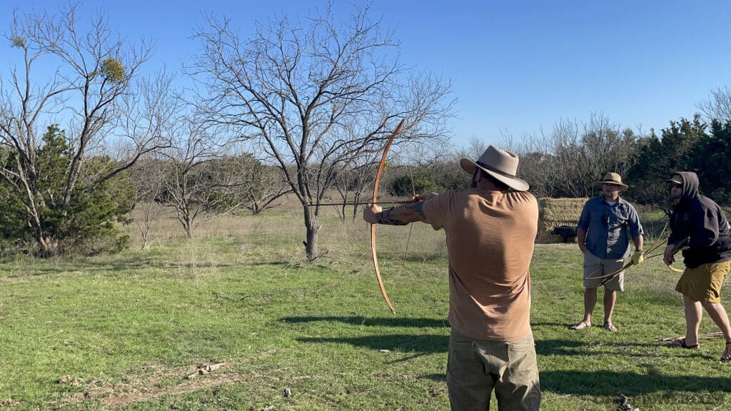 Photo of Phillip testing the draw length of a handmade bow.