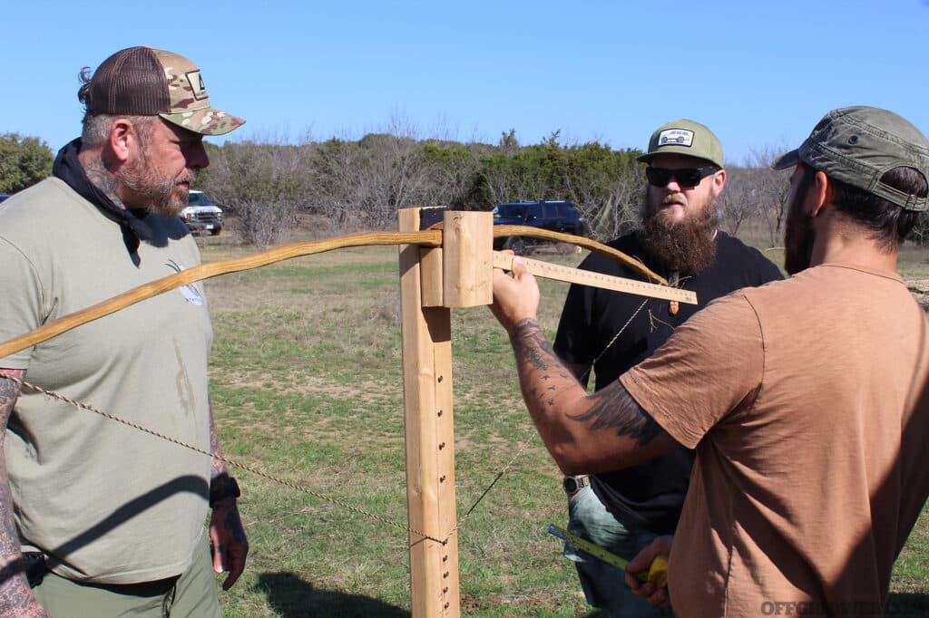 Photo of Phillip and his primitive wilderness survival students using a tillering jig to make sure their bow is bending enough.