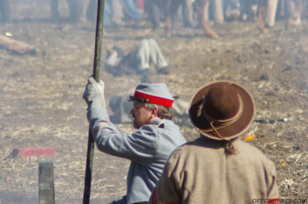 A civil war soldier sits, dazed, looking over the battlefield.