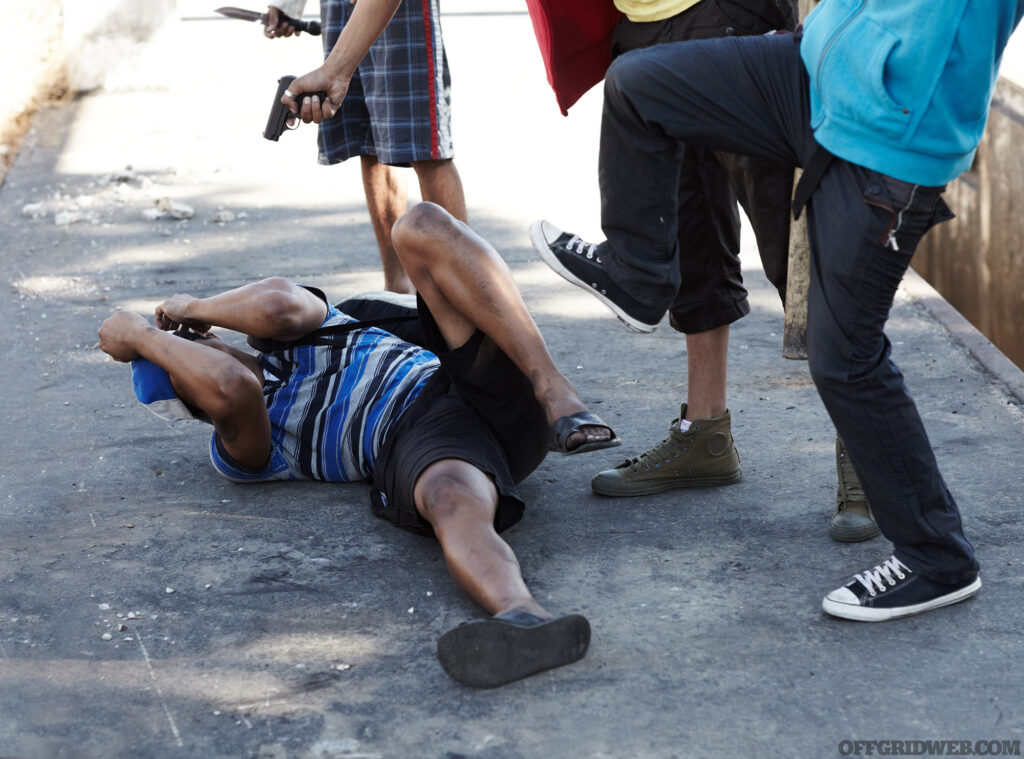 Cropped image of a man being beaten on the ground by a gang.