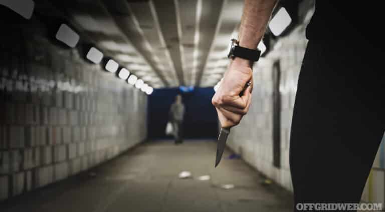 Crime robbery concept. A robber or a killer person with a sharp knife about to commit a homicide in a tunnel.