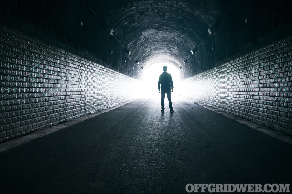 Man standing silhouetted in a dark tunnel.