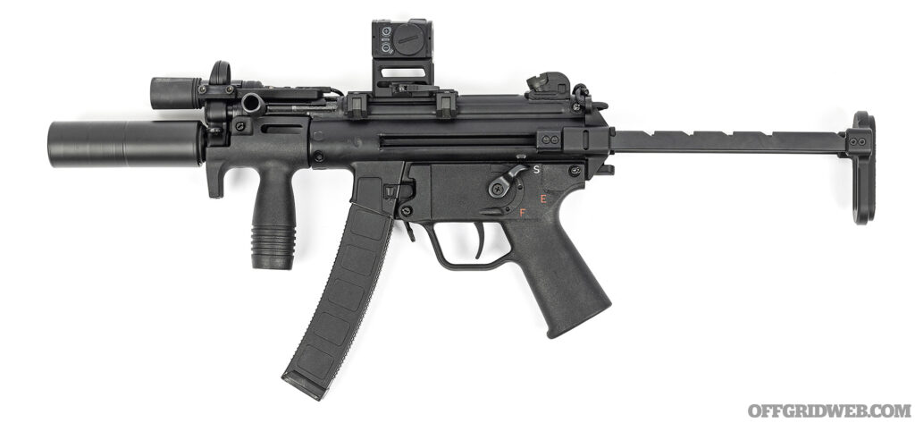 Studio photo of an MP5K paired with an MFI ultra-low-profile claw mount from HKParts, the B&T skeletonized riser on our Aimpoint ACRO red dot allows unobstructed use of the factory iron sights.