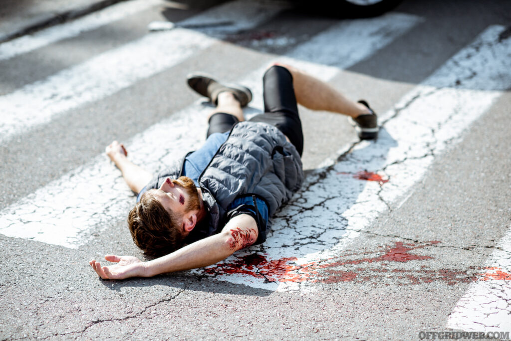 Injured bleeding man lying on the pedestrian crossing after the road accident.