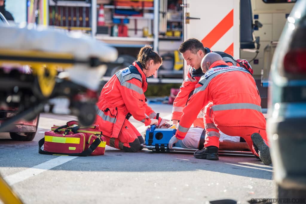 Paramedics providing first aid to man injured in car accident.