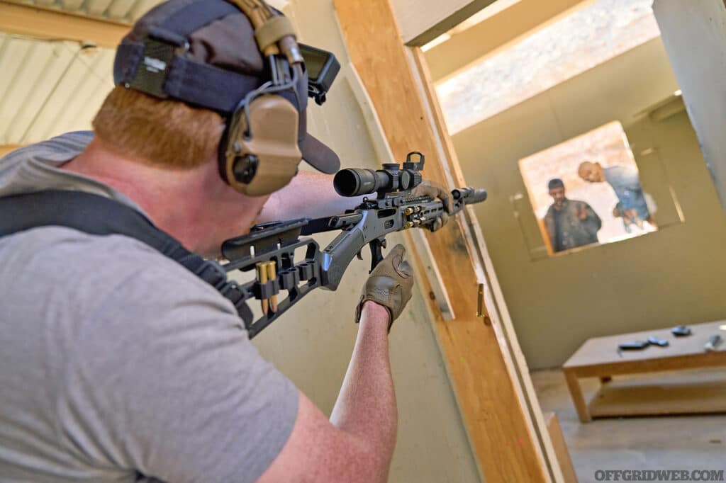 Photo of man shooting at CQB targets inside a door frame.