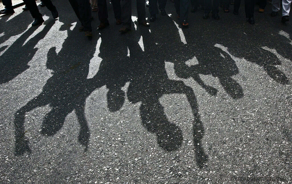 Protesters cast a shadow as they march on a street.