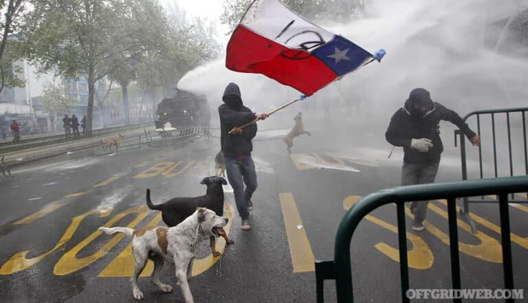 A student waves a Chilean flag as a riot police vehicle releases a jet of water during a protest against the government to demand changes in the public state education in Santiago, September 27, 2012. Chilean students have been protesting against what they say is profiteering in the state education system. REUTERS/Ivan Alvarado (CHILE - Tags: POLITICS CIVIL UNREST)