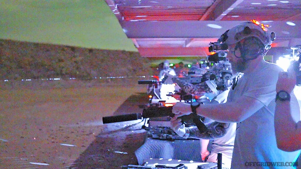 Photo of firearms being fired at a night vision range as seen through colored digital night vision.