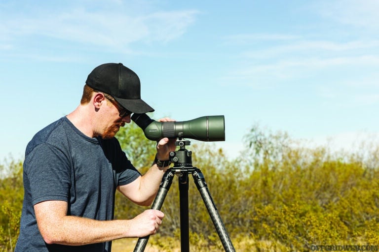 Featured image for the pros and cons of optics article. An adult male is looking down through a spotting scope.