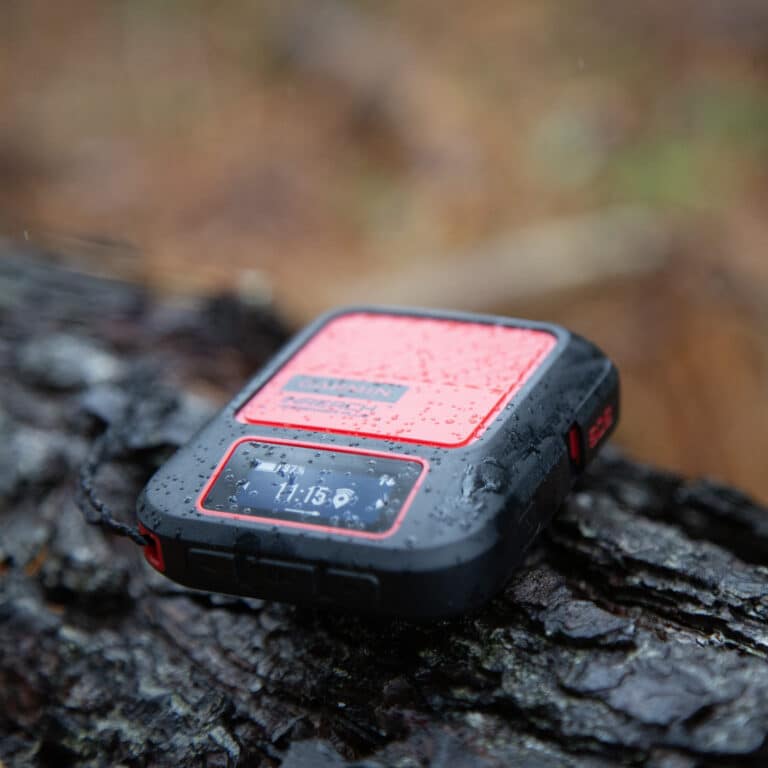 A garmin inreach on a wet log.
