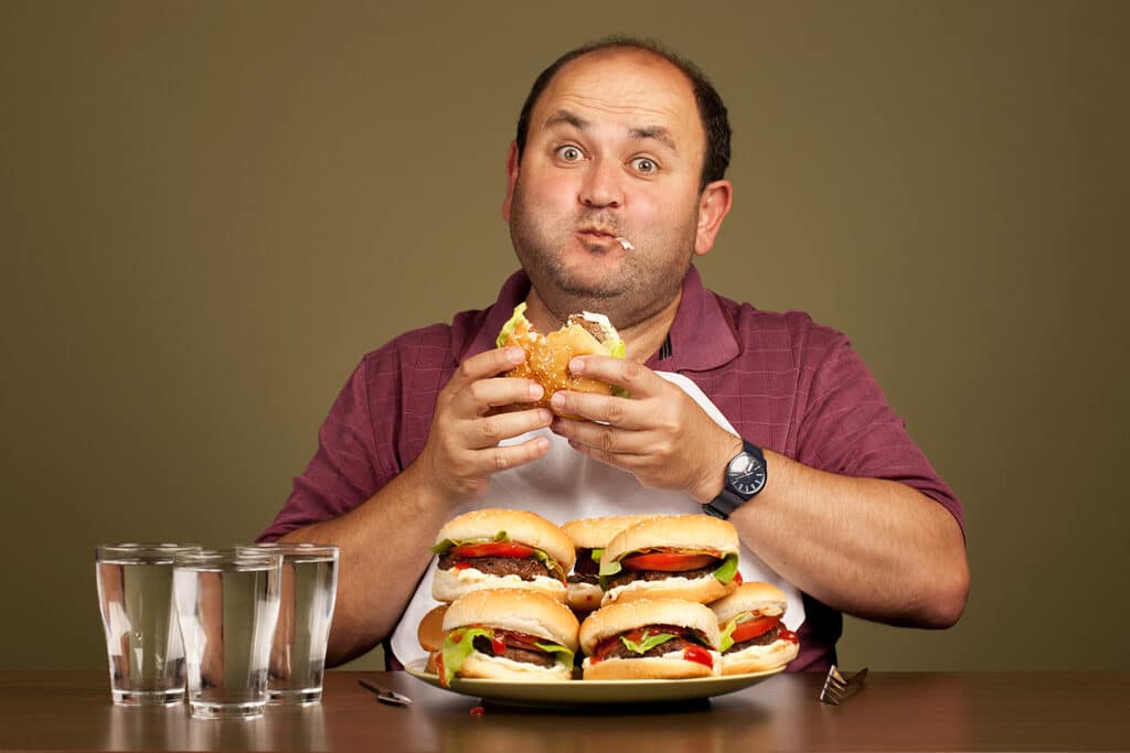 man with several cheeseburgers